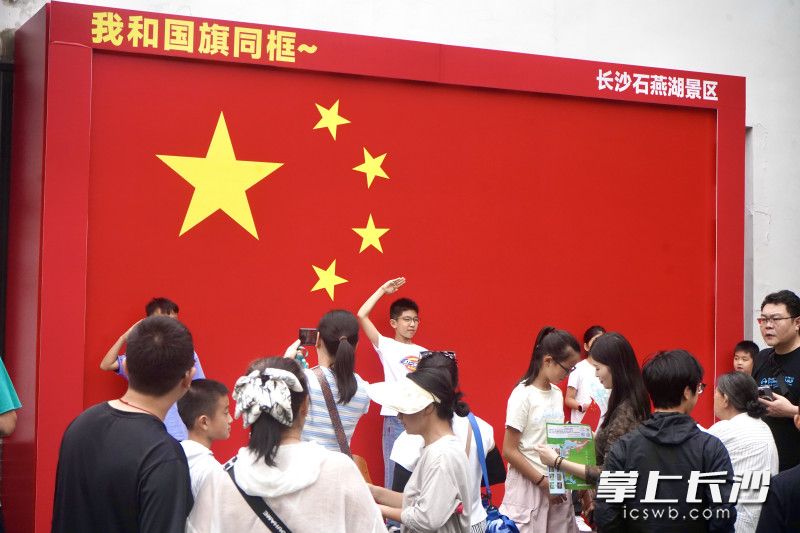 游客在与国旗同框打卡。今日，前来石燕湖景区游玩的人仍络绎不绝。均为长沙晚报全媒体记者 贺文兵 通讯员 彭杜 摄影报道