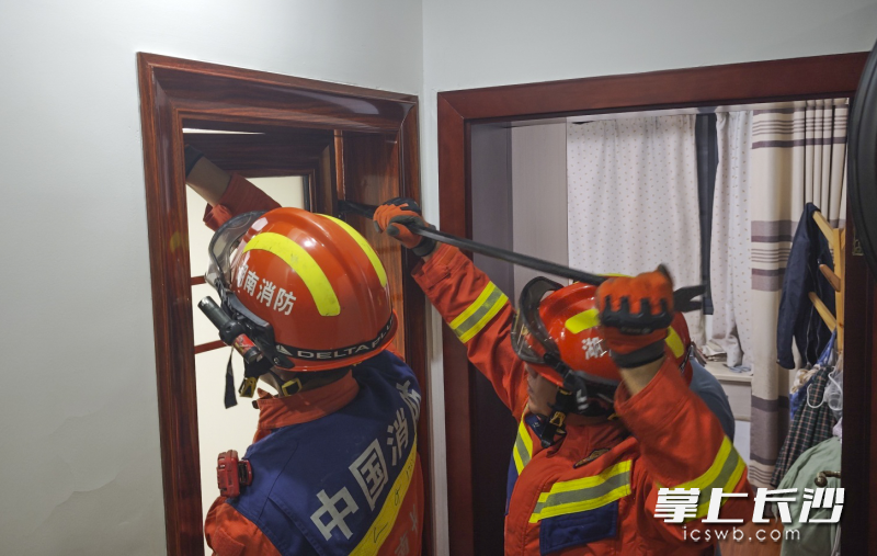 消防员正在破门营救。 长沙晚报通讯员 肖博文 摄