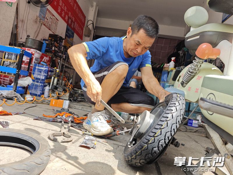 罗先喜正在忙着为电动车换轮胎。均为长沙晚报全媒体记者 贺文兵 摄