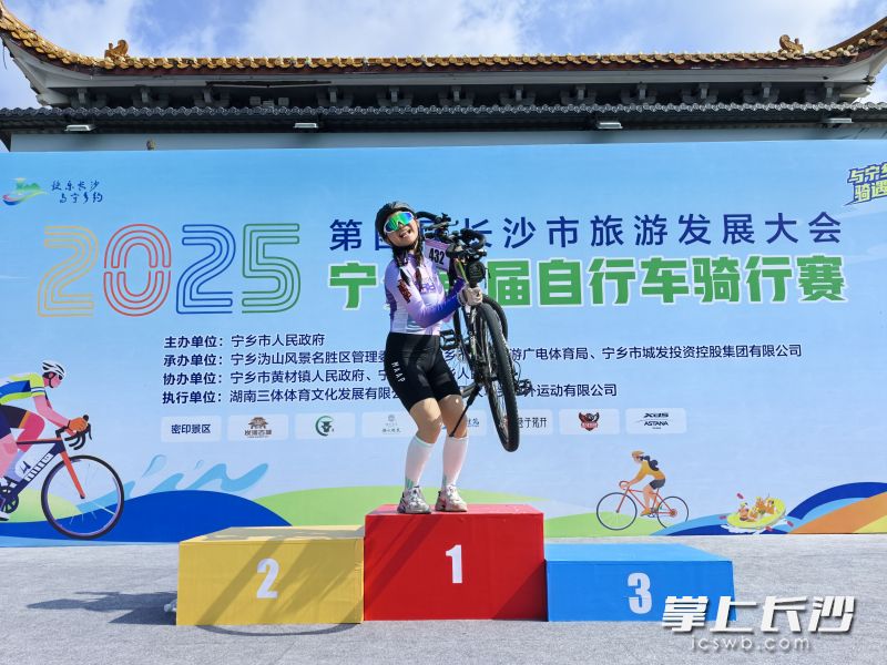 一名率先到达终点的女骑手,兴奋地举起了自己的爱车。 一名率先到达终点的女骑手,兴奋地举起了自己的爱车。