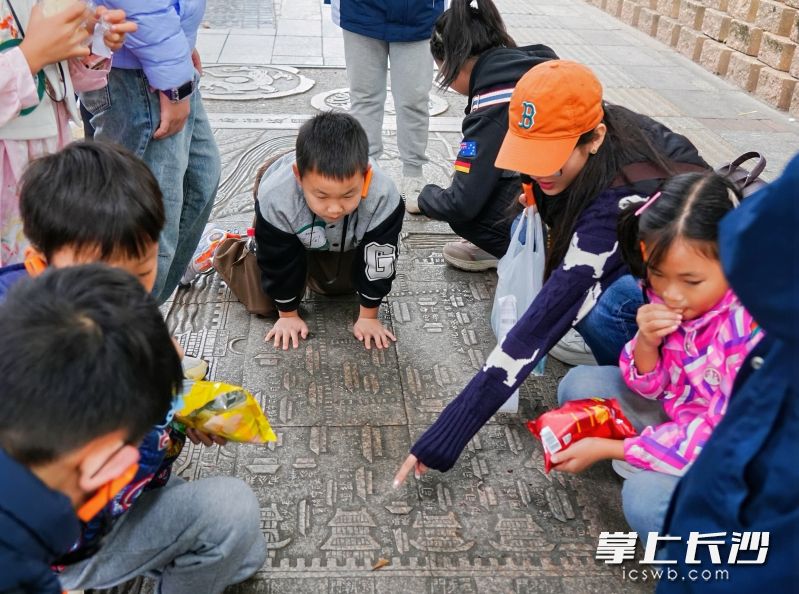 小朋友们在街头细细观看老长沙地图雕刻。 小朋友们在街头细细观看老长沙地图雕刻。