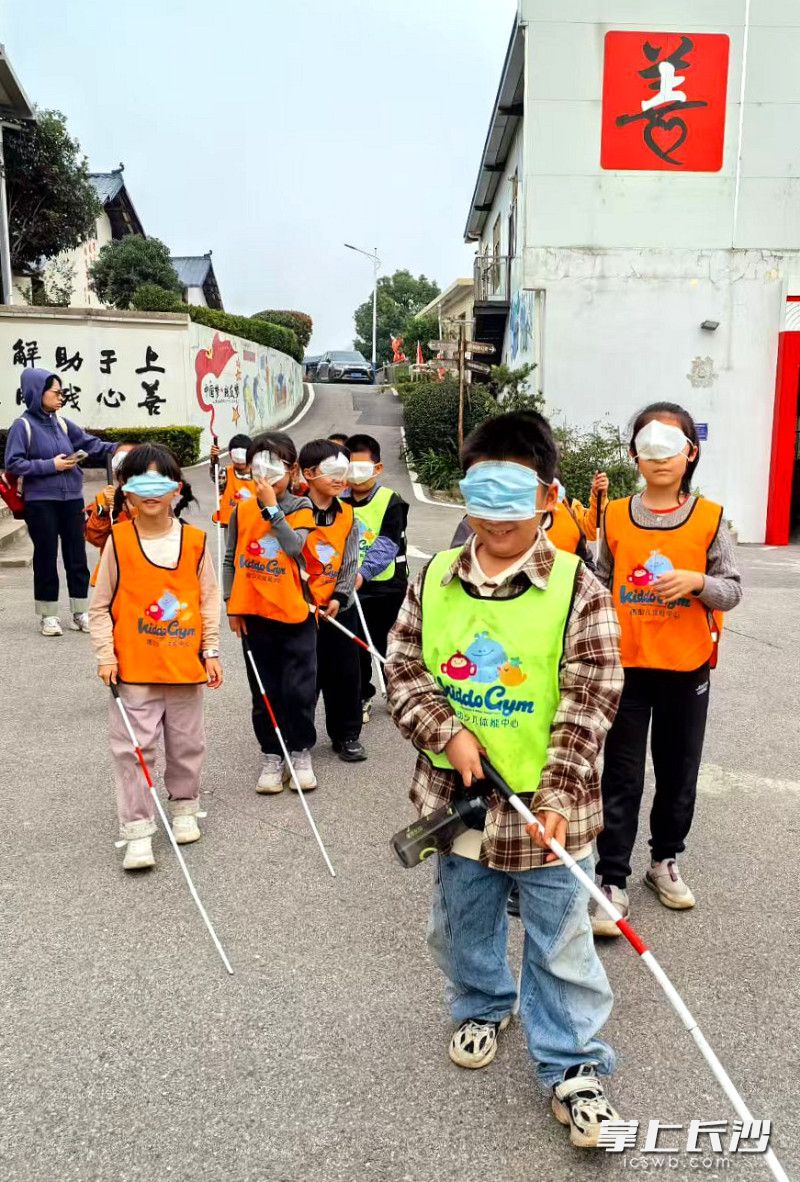 在“盲人走路”体验区，孩子们戴上眼罩，在黑暗中小心翼翼地摸索前行。