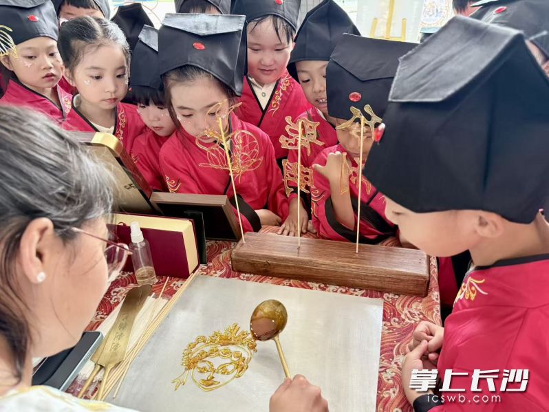 糖画传承人尹剑钊在长沙市第一中学附属小学教孩子们做糖画版戏曲人物。