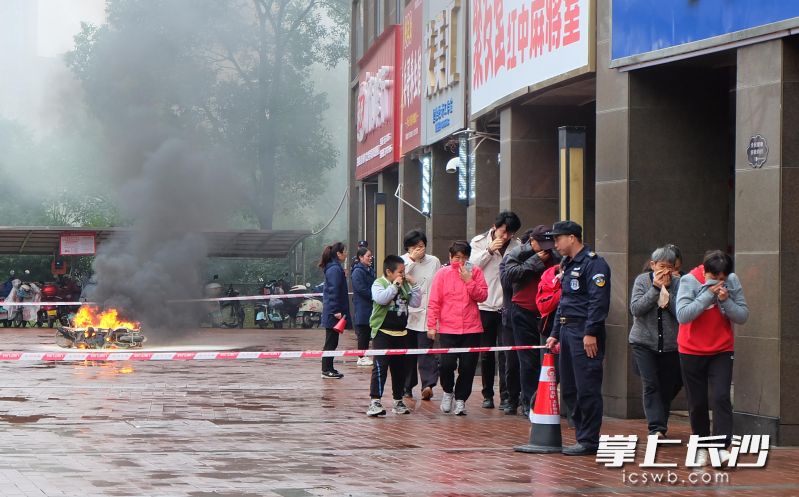 居民们在物业小区工作人员疏导下，从安全通道有序撤离。