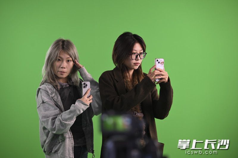 两位观众在虚拟拍摄镜头前摆pose。