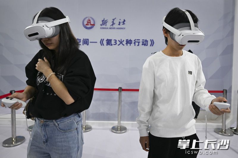 两位观众在体验新华社推出的《氦3火种行动》。