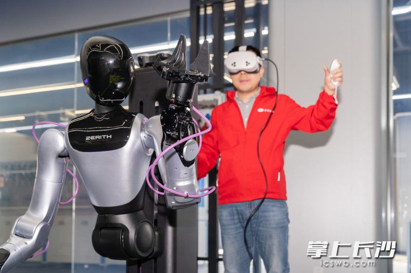 工作人员佩戴VR设备操控机器人。 工作人员佩戴VR设备操控机器人。