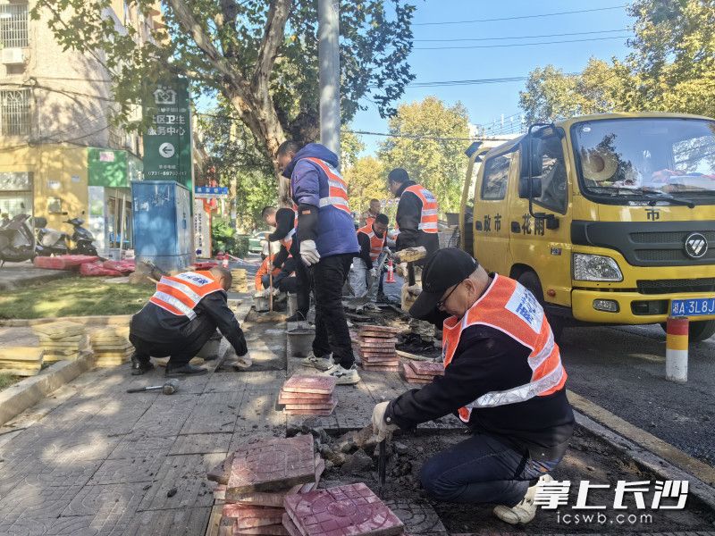 市政工人正蹲在人行道上，仔细撬起一块块磨损的盲道砖，换上新铺设的麻石板。 全媒体记者 周游 摄