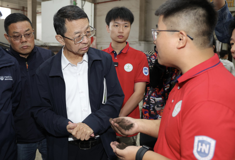 海南东方有机循环利用科技小院学生正在向张福锁院士（左）及评审专家介绍其主导研发的有机肥。王晓 摄