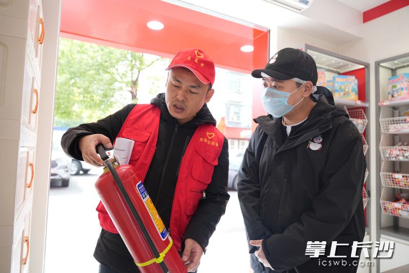 社区志愿者上门检查门店的消防设施。