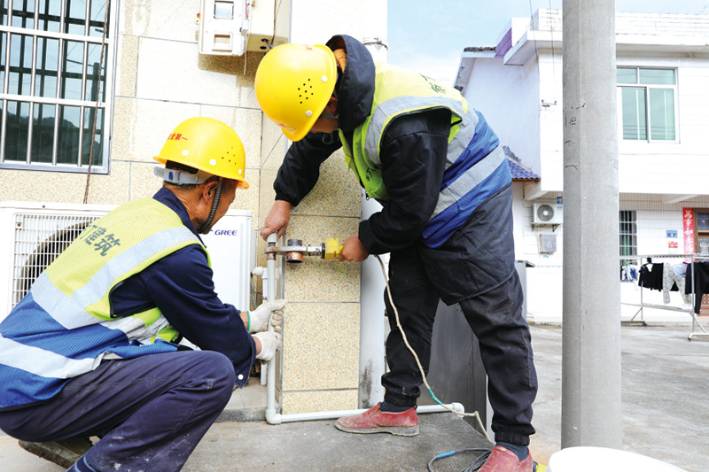 洞阳镇砰山村，施工人员将水管铺设到户。刘珂摄
