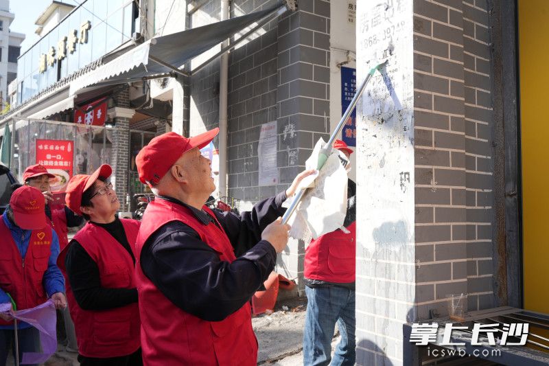李枝湘和志愿者们清除墙上的小广告。