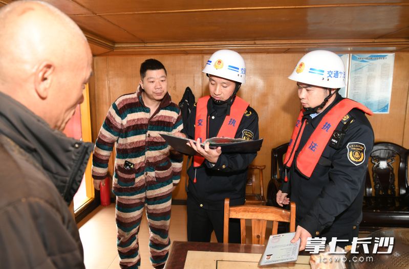 执法人员对船舶进行安检，并对船舶工作人员进行安全提醒。