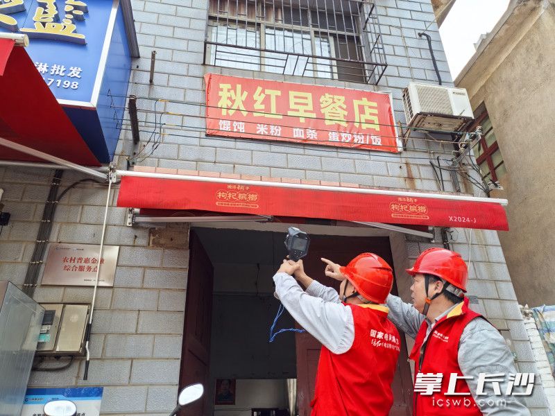 工作人员排查商铺招牌电线隐患。通讯员供图