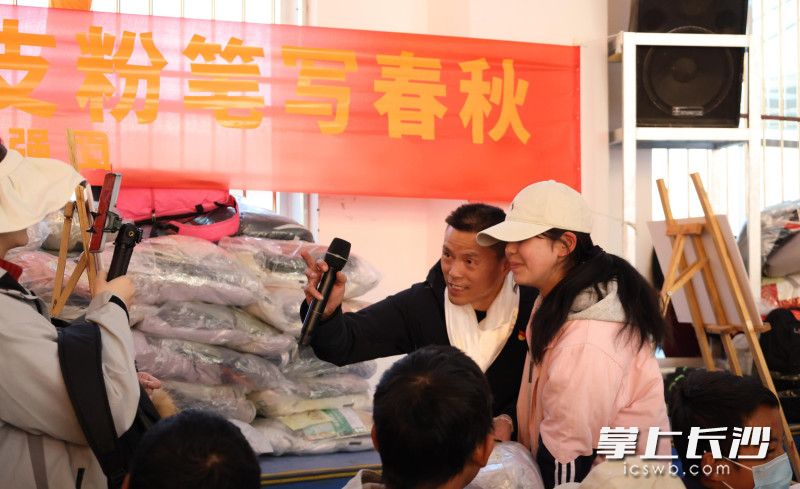 12月8日，嘤鸣慈善发起人唐林（中）和受捐学生在捐赠仪式现场互动。