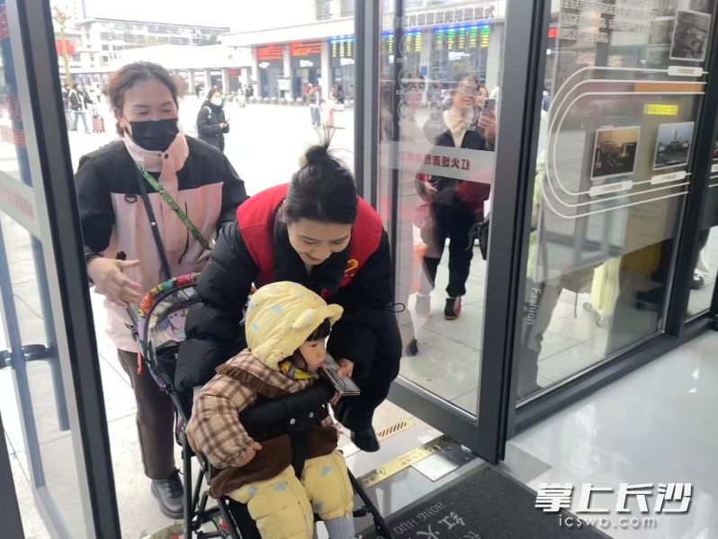 志愿者帮助旅客进“红火炬”雷锋志愿服务站休息。