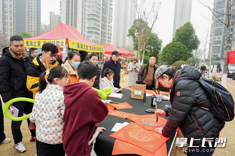 书法爱好者现场挥毫送福，“马年大吉行好运”等吉祥春联被居民争相领取。