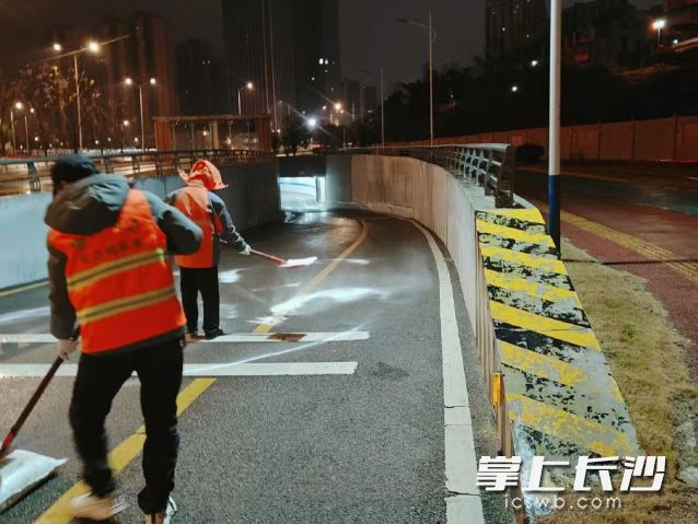 工作人员正在地下通道抛洒融雪剂，防止结冰。  长沙晚报通讯员 谭甜 供图