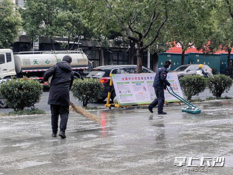 上午，学校党员干部在校门口扫雪，确保中午放学时孩子们出行安全。