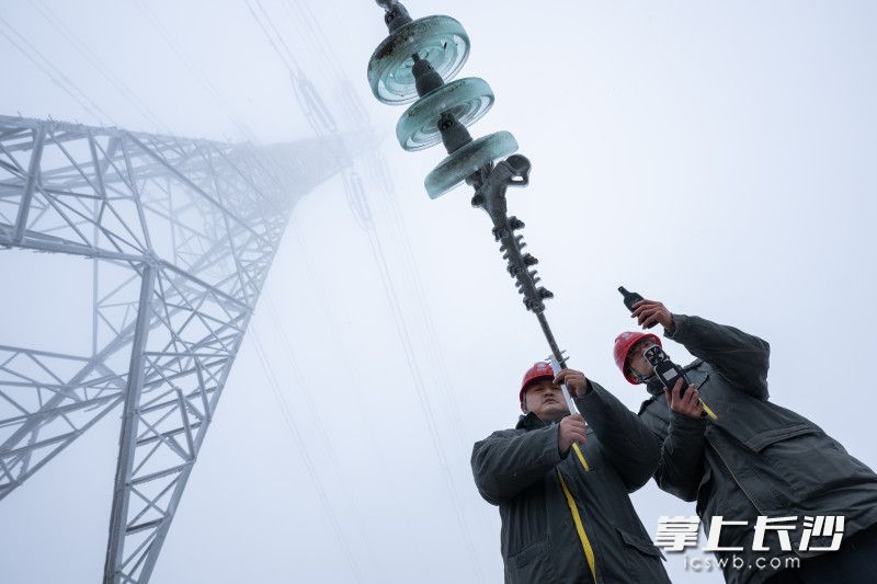 输电运检人员张丰(左)、蒋正湘对220千伏浏集Ⅰ线34号杆塔开展覆冰情况监测。 输电运检人员张丰(左)、蒋正湘对220千伏浏集Ⅰ线34号杆塔开展覆冰情况监测。