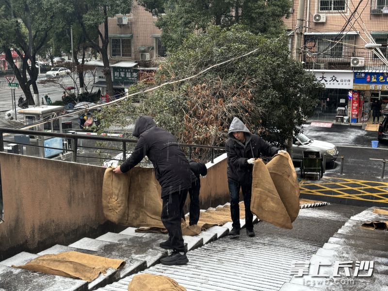 荷晏社区工作人员在小区门口铺放防滑麻袋。
