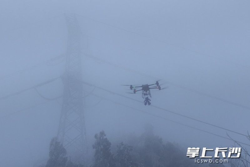 无人机吊装除冰机器人前往覆冰线路作业。 无人机吊装除冰机器人前往覆冰线路作业。