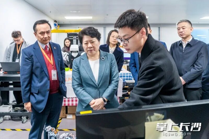 吴桂英在香港科学园，参观物流机械人研究中心。