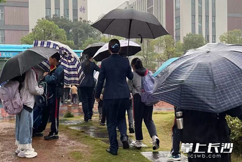 下雨天，湖南银行长沙分行辖内浏阳金阳新城支行工作人员主动为候车学生撑伞护送。  通讯员供图