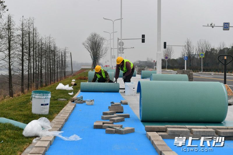 工作人员在铺设塑胶跑步道。