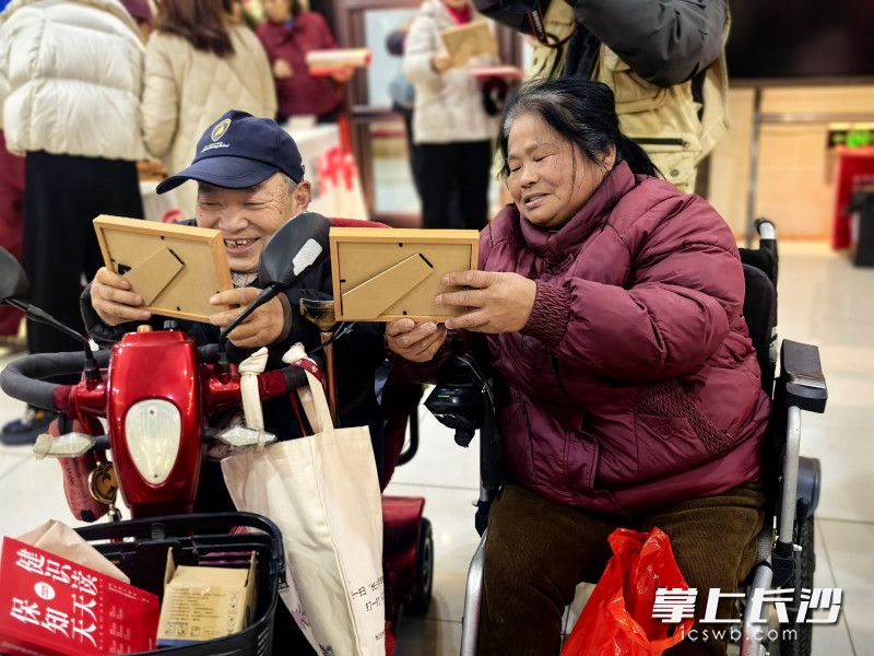 看着手中即时打印、装裱的照片，居民们露出幸福的笑容。