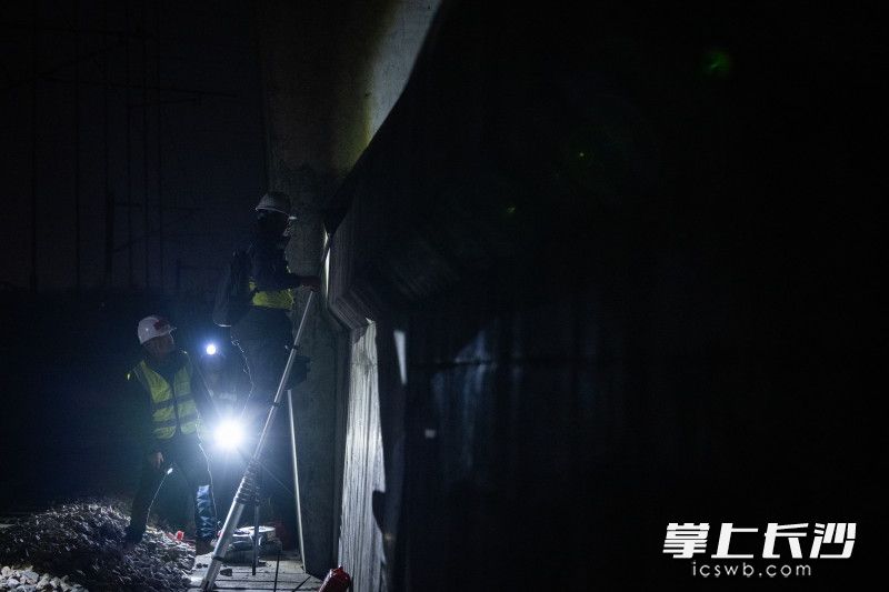 夜色中，作业人员争分夺秒攀爬桥台。