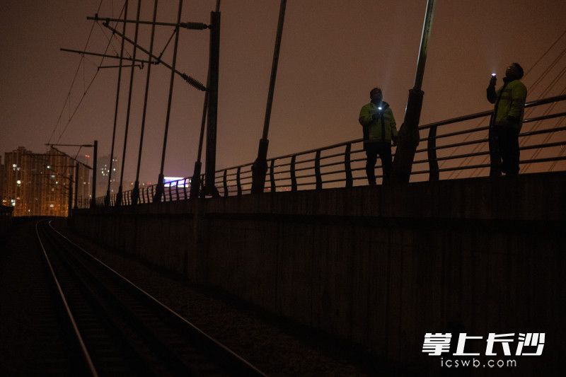 在夜色中，工作人员在用手电进行目视检查。