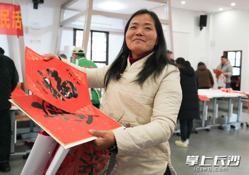 芦江社区居民石女士一边接过春联，脸上写满了喜悦。