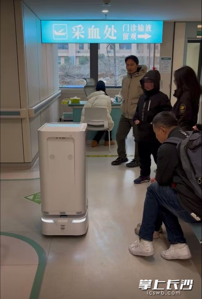 湖南湘江新区东方红街道社区卫生服务中心二楼采血区，一台智能物流机器人正在工作，吸引居民纷纷驻足。 均为长沙晚报通讯员吴敏敏、阳哲供图