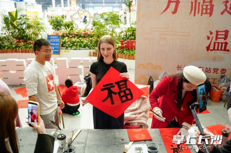 工作人员为旅客赠送福字对联。