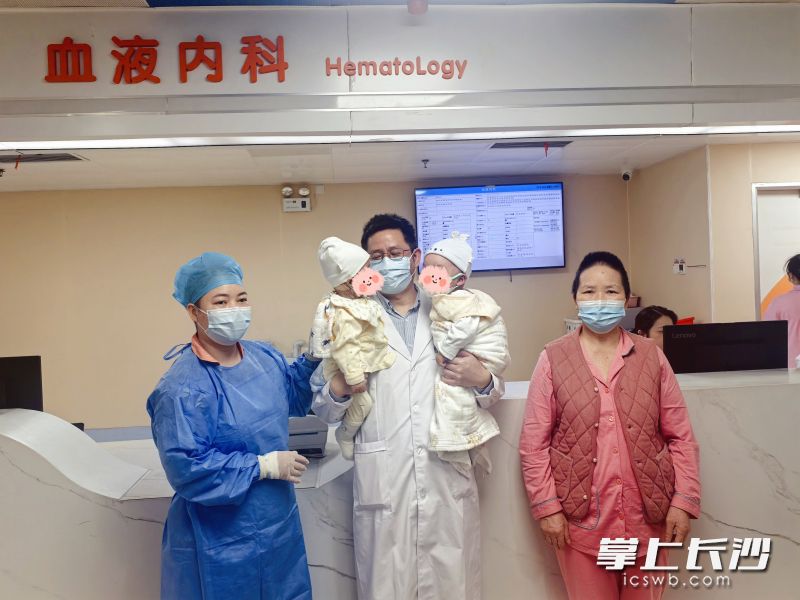 湖南省儿童医院血液内科主任张本山（中）与出仓的双胞胎及家人在一起。 医院供图