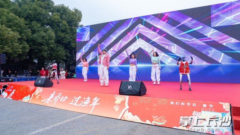 歌舞表演《马年STYLE》中，两位智能机器人身着喜庆花棉袄，迈着灵动的步伐，与台上的村民演员同台共舞。