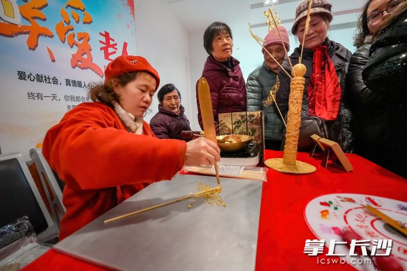 糖勺流转,缕缕金丝凝固成生肖糖画,引来居民围观。 糖勺流转,缕缕金丝凝固成生肖糖画,引来居民围观。