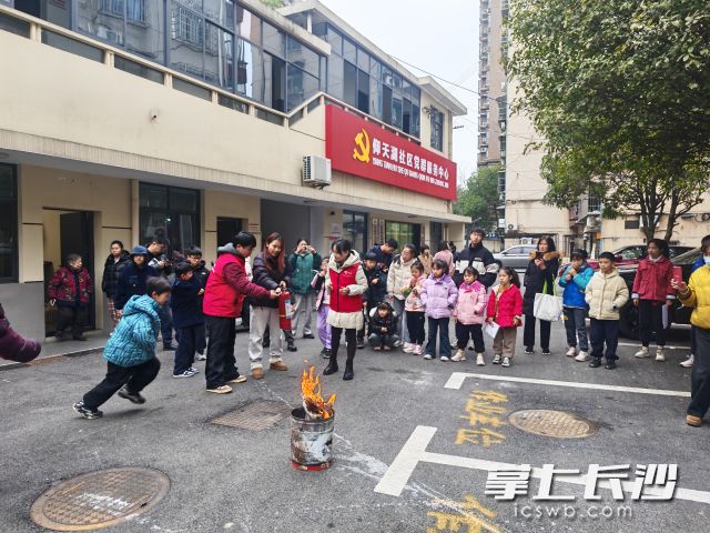 学生、家长与志愿者共同参与灭火器实操训练。 学生、家长与志愿者共同参与灭火器实操训练。