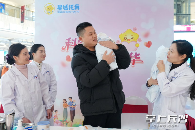 一位年轻男士认真学习抱娃姿势。