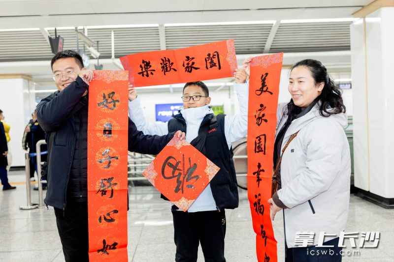 一家三口展示春联和福字。