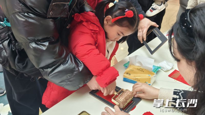 孩子们在家长的陪伴下，手持传统滚轮印章，巧手印上对新年的美好祝福。