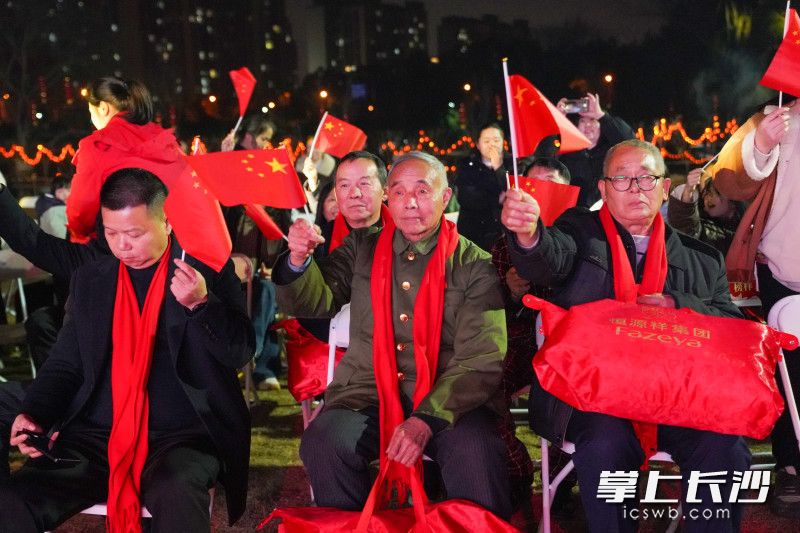 激昂的《歌唱祖国》旋律响起，市民们挥舞着国旗齐声合唱。