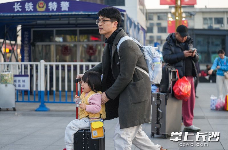 一位家长推着小孩赶路。