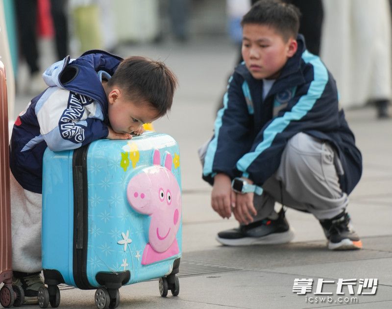 一位小朋友趴在行李箱上玩耍。