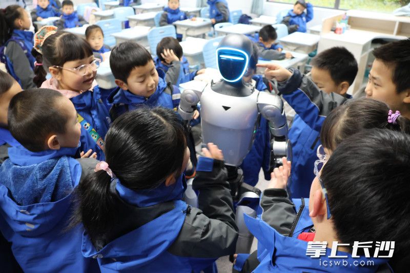 教室里，学生们围着机器人不停提问，充满好奇。