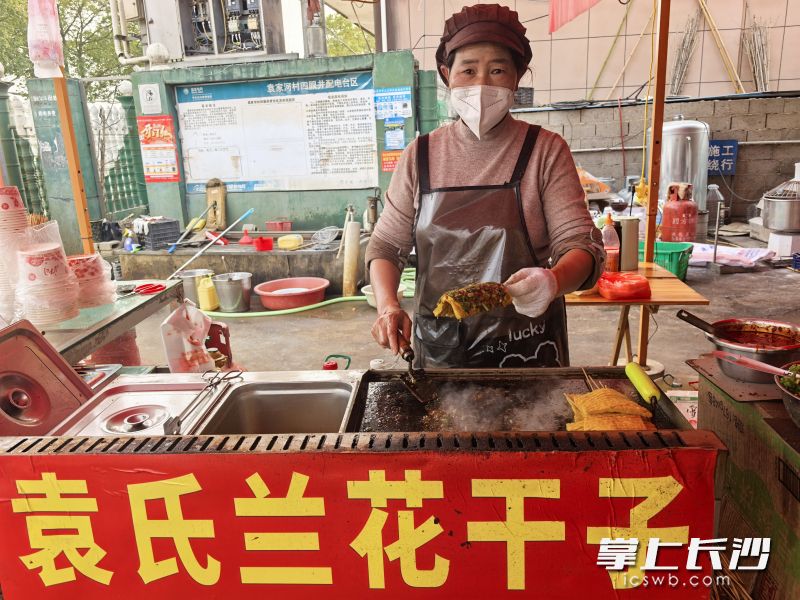 经营“袁氏兰花干子”的大嫂，一边翻动铁板上的兰花干子，一边笑着跟记者拉家常。