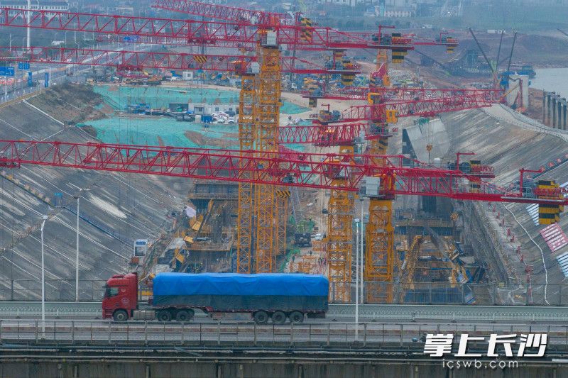 3月18日，湘江长沙综合枢纽三线船闸工程建设现场十余个塔吊下，各种工程车辆有序进出，一片繁忙景象。 均为长沙晚报全媒体记者黄启晴摄