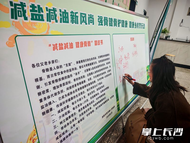 村民在“减盐减油”健康骨骼倡议展板上签名。