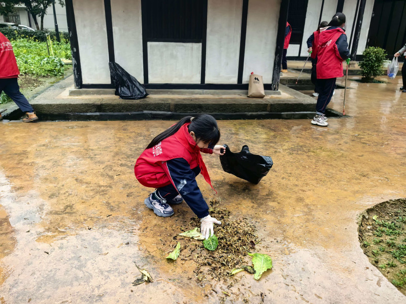 孩子们拿起工具，分组协作，认真清扫旧址及周边的环境卫生。